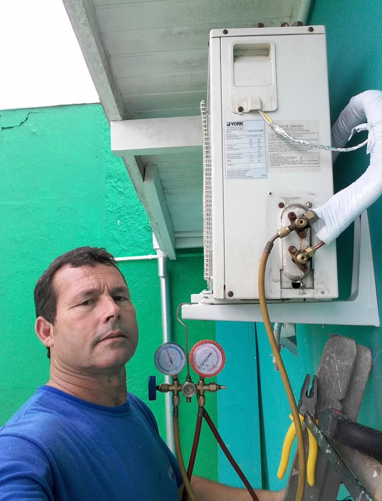 Técnico da Moura ao lado de condensadora com manifold de pressão